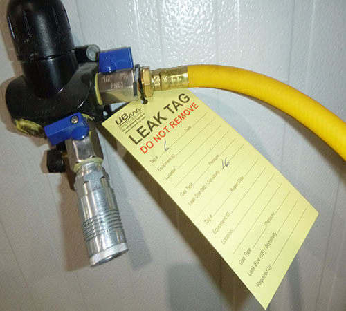 yelllow hose attached to a device with a yellow tag attached that indicates a leak