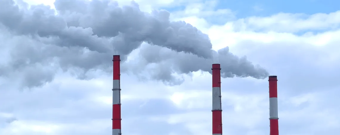 Three industrial smoke stacks expel smoke into atmosphere