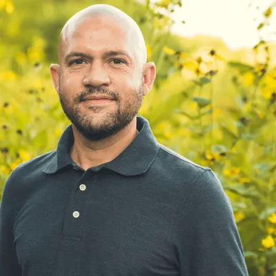Jason Clay standing before field of yellow flowers